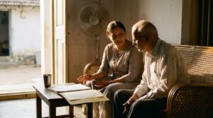 A daughter sitting with her elderly father, going through family papers at home in Karnataka